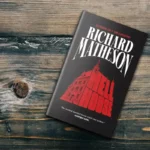 Book cover of Hell House by Richard Matheson on dark wooden surface