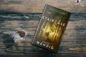 The Staircase in the Woods by Chuck Wendig book cover photographed on wooden surface
