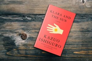 Klara and the Sun by Kazuo Ishiguro lying on a wooden surface, showing the red hardcover design