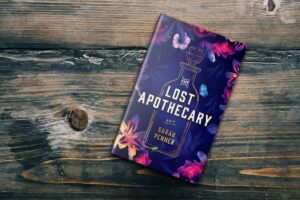 The Lost Apothecary by Sarah Penner lying on a wooden surface