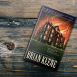 Book The Complex by Brian Keene on a wooden table